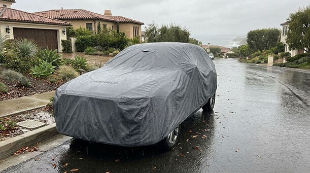Van under a waterproof DaShield cover on a rain-soaked driveway