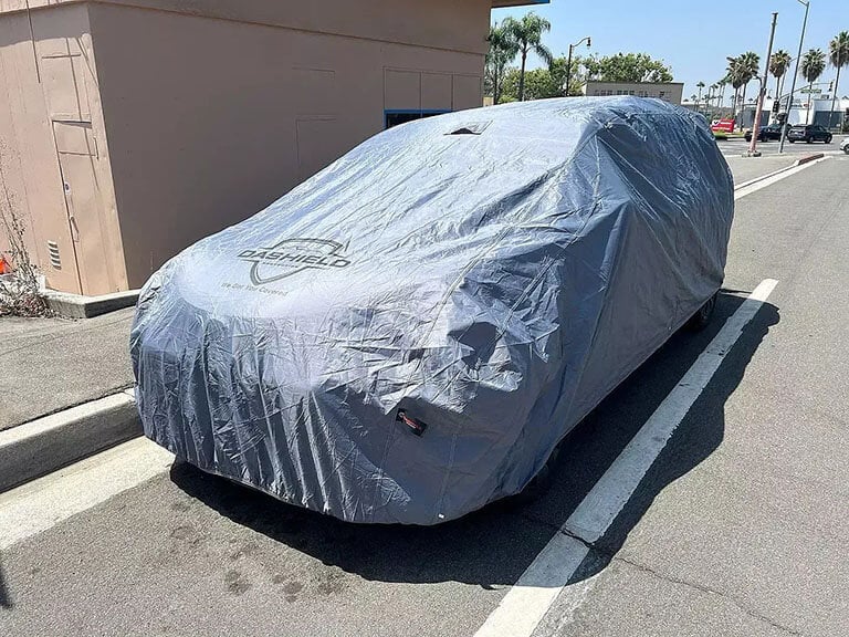 Car cover on an SUV in a sunny parking lot