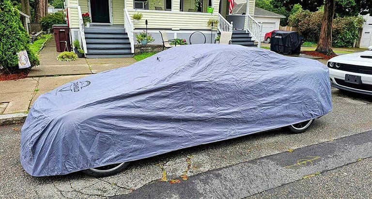 Car cover protecting a sedan parked next to a motorcycle