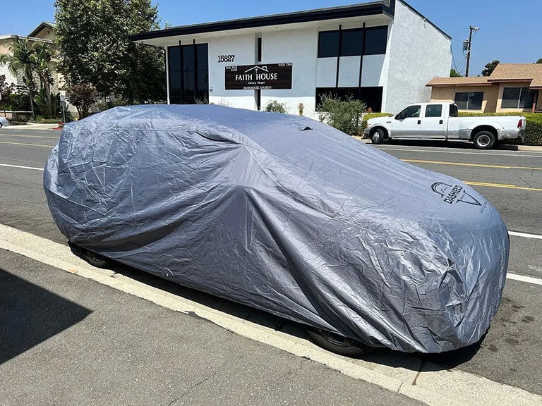 Full car cover on a sedan parked outdoors