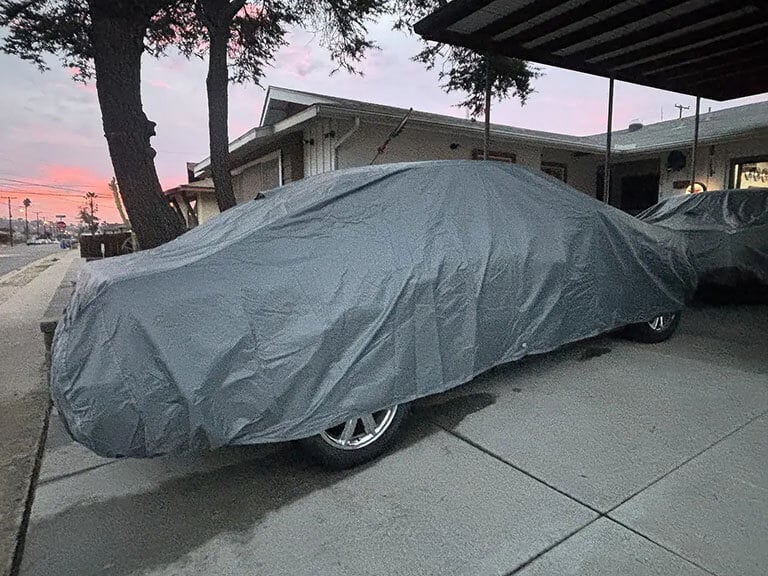 USCarCover protecting a sedan in a warm-climate driveway at dusk