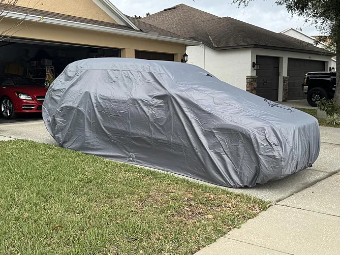 SUV covered outdoors with autumn leaves piled on the cover